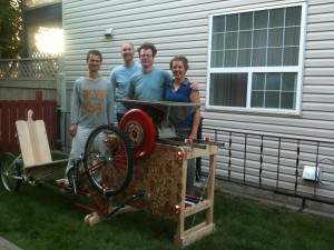Mike Johnson (centre-right) stands behind Operation Fruit Rescue Edmonton's pedal-powered apple crusher.  Source: OFRE